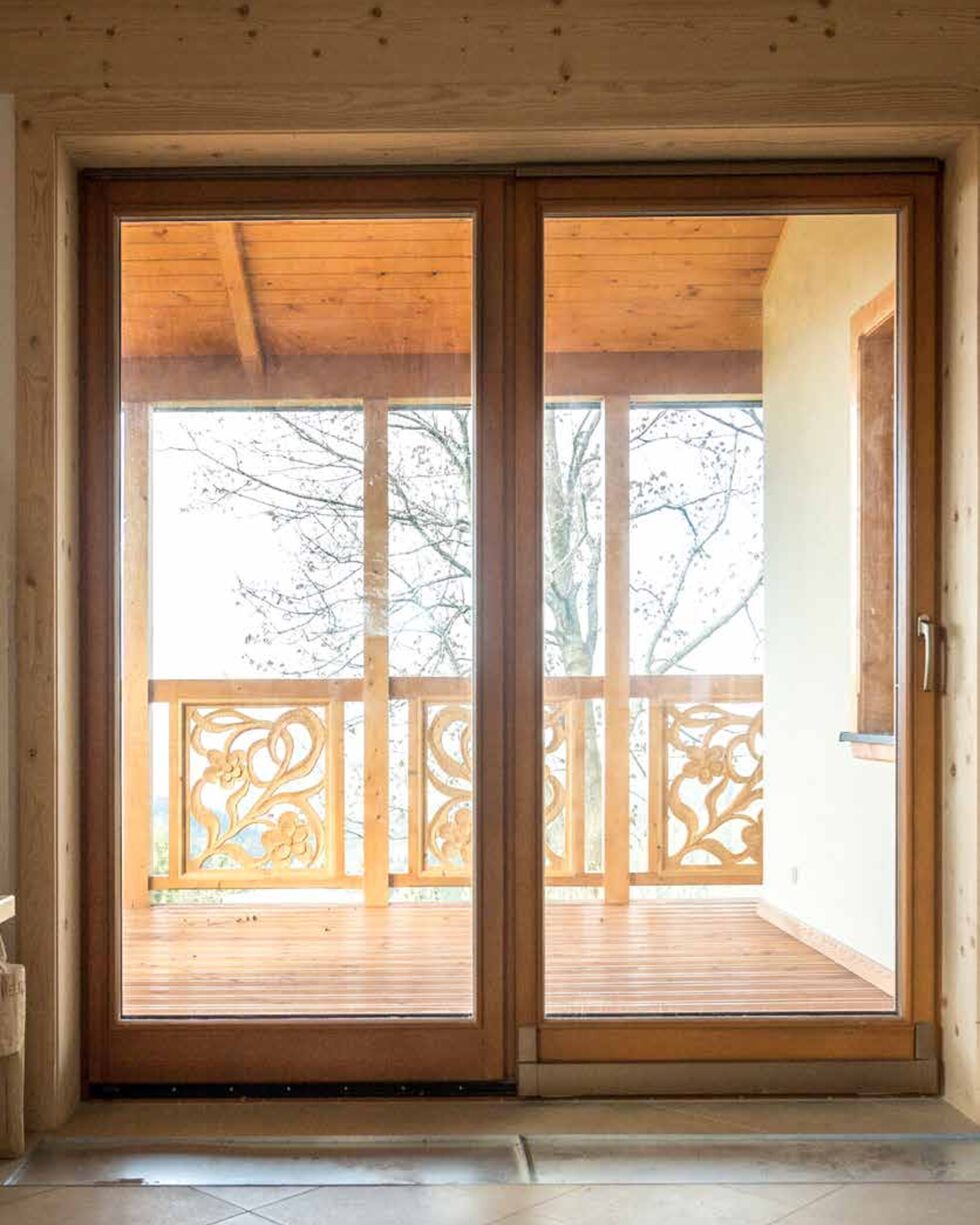 Porte-fenêtre coulissante en bois ouverte sur un balcon