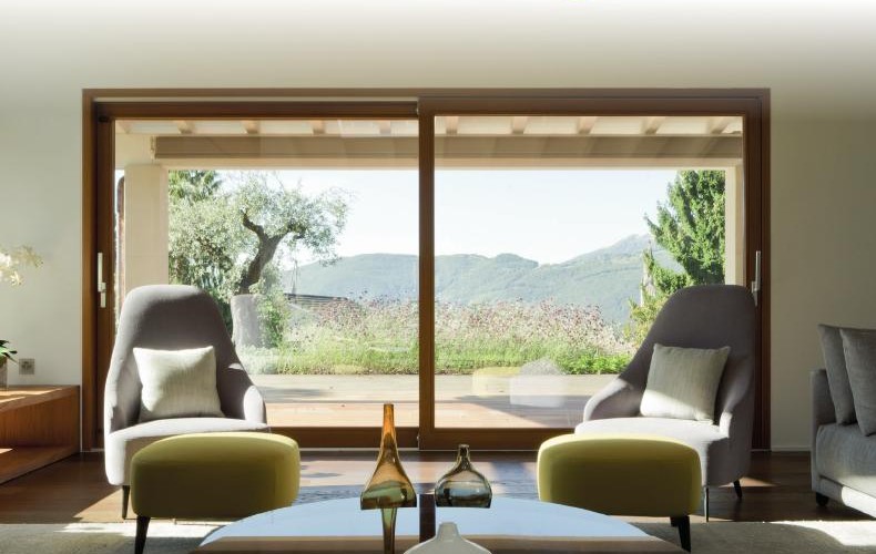 Grande baie coulissante ouvrant un salon sur le jardin et les montagnes